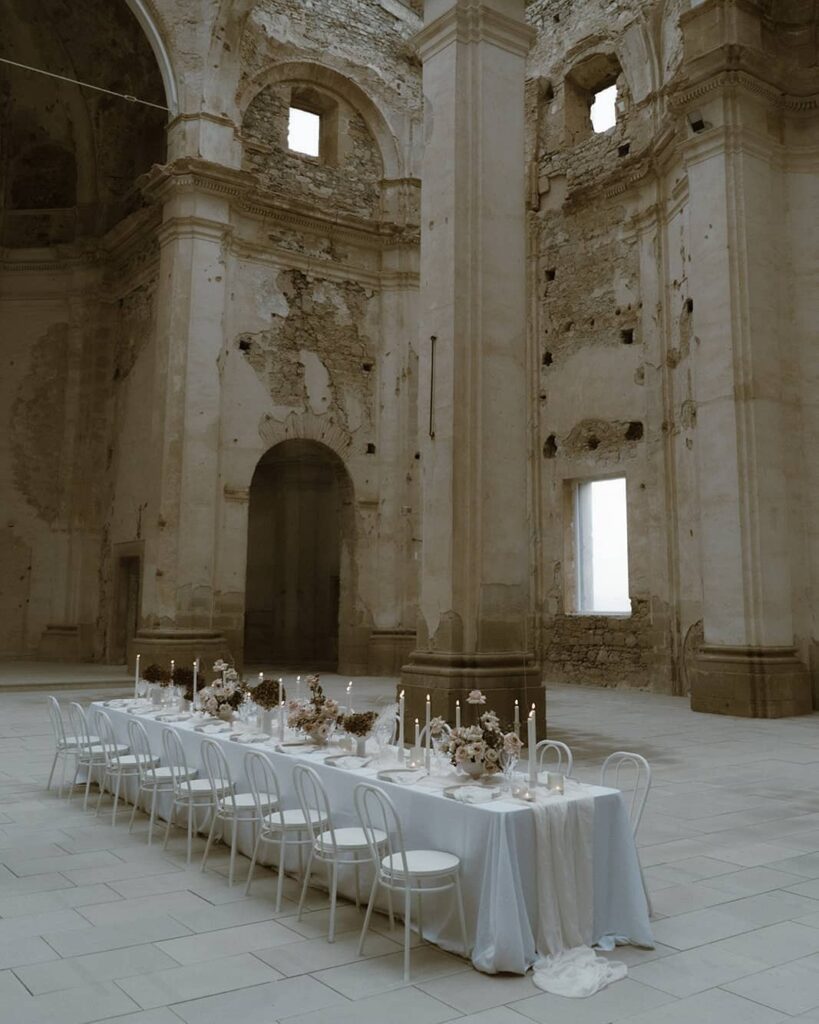 Tavola imperiale per Micro Wedding di lusso allestita in una chiesa sconsacrata con candele e fiori bianchi